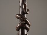 sculpture of a snake wrapped around a tree branch on a gray background
