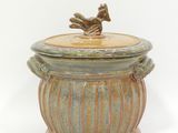 a ceramic container with a bird on top