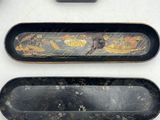 three black and gold trays and a black box on a white table