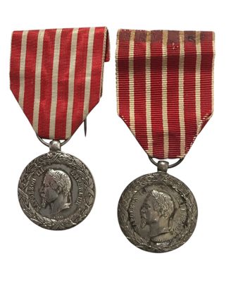 deux médailles ornées d'un ruban rouge et une médaille d'argent sur fond blanc