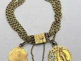 a close up of a gold necklace with two medallions on it