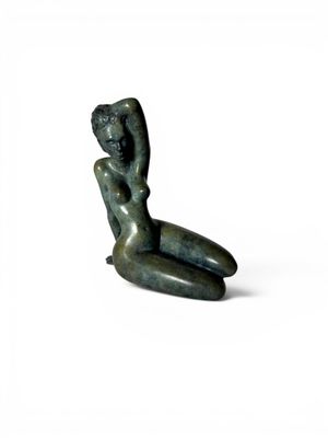 statue d'une femme assise, le dos appuyé contre une surface blanche