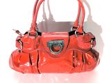 un sac à main rouge posé sur une surface blanche, avec une ombre