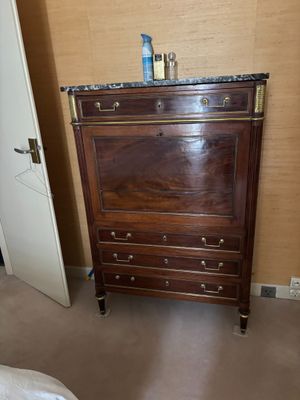 une commode dans un coin d'une chambre où se trouve un lit
