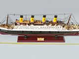 une maquette de bateau posée sur un socle à côté d'une règle