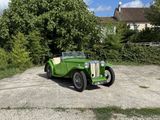 une voiture verte garée sur un parking à côté d'une maison
