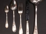 five silver spoons and two silver spoons on a black table