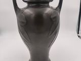 a black vase sitting on a white surface next to a book