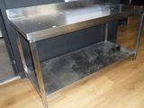 a stainless steel table in the middle of a wood floor