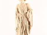 une vieille statue représentant un homme vêtu d'une robe et coiffé d'un chapeau