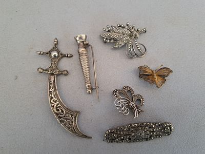 a lot of silver brooches on a white surface