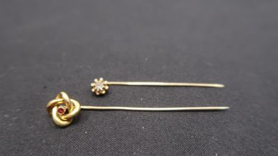 a pair of gold tone hair pins with a red stone
