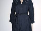 La robe est en lin bleu foncé et présente une ceinture à la taille.