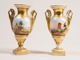 two gold vases with paintings on them sitting on a white surface