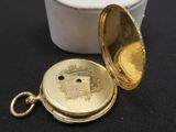 a gold pocket watch sitting on a table next to a white container