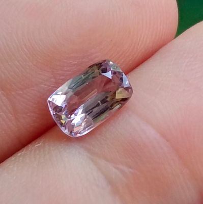 une personne tient un diamant rose dans la main, sur un fond vert