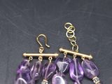 a close up of a pair of earrings with purple beads