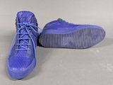 pair of blue sneakers with laces on them sitting on a white surface