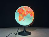 un petit globe lumineux posé sur un socle, sur une table