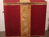 an old red and gold chest with a gold stripe on the front