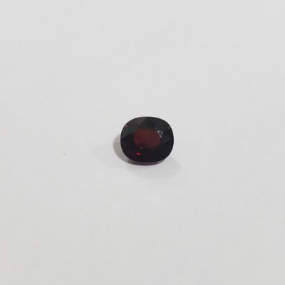 une pierre de grenat rouge posée sur une surface blanche