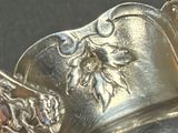 a silver vase with a flower on it sitting on a table