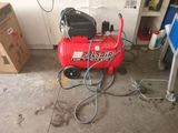 a red air compressor sitting on the floor in a garage