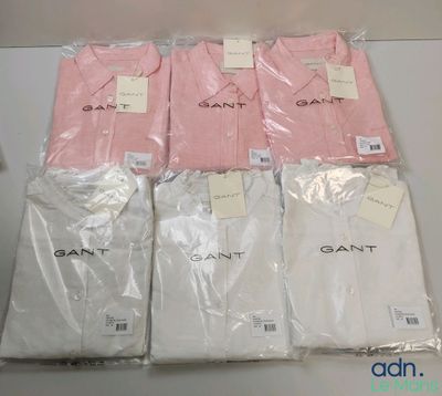 Quatre chemises roses et une chemise blanche sont posées sur une table