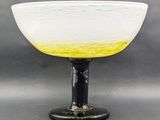 yellow and white glass bowl sitting on top of a black base