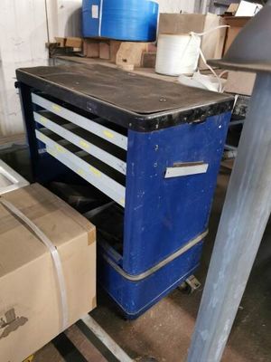 un établi bleu avec des tiroirs et une caisse posée par terre