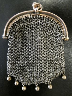a silver chainmail purse with pearls hanging from it
