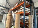 de nombreux rouleaux de papier posés sur une étagère dans un entrepôt