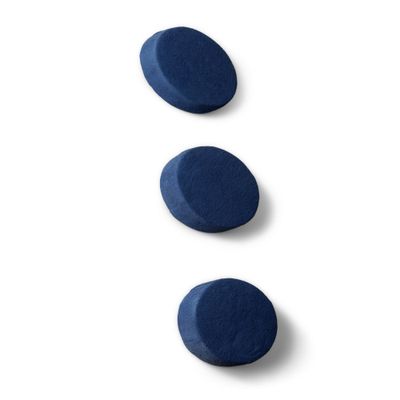 trois comprimés bleus sont disposés les uns au-dessus des autres sur une surface blanche
