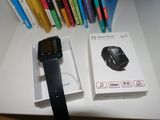 a black smart watch sitting next to a box of pens