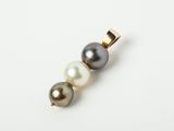 a close up of a pearl and gold pendant on a white surface