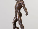 bronze statue of a man holding a bottle in his hand