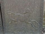 a stone plaque with a horse on it next to a brick wall
