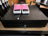 two cell phones sitting on top of a cash register