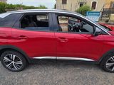 La voiture rouge est garée sur le bord de la route, dans le parking.