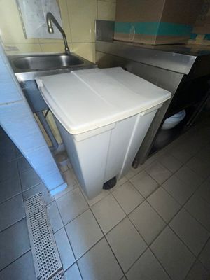 une poubelle blanche posée dans une cuisine, à côté d'un évier