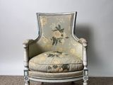 an old chair with a floral upholstered back and a floral upholstered seat