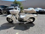 a white motorcycle parked in a parking lot with other cars