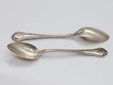 two spoons that are sitting on a white surface