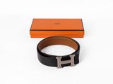 une ceinture noire et orange avec une boucle argentée, posée devant une boîte