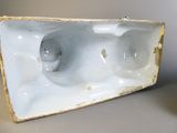 un objet en porcelaine blanche percé de trous, posé sur une table
