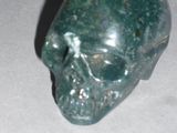 a green stone skull sitting on a white surface