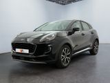 Une voiture noire est garée dans une grande pièce aux murs blancs.