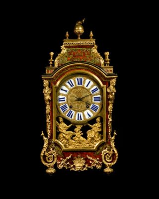 a gold and red clock with roman numerals on it