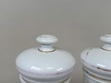 two white ceramic jars with gold trims on them