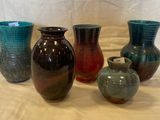 Plusieurs vases de différentes couleurs sont alignés sur une table